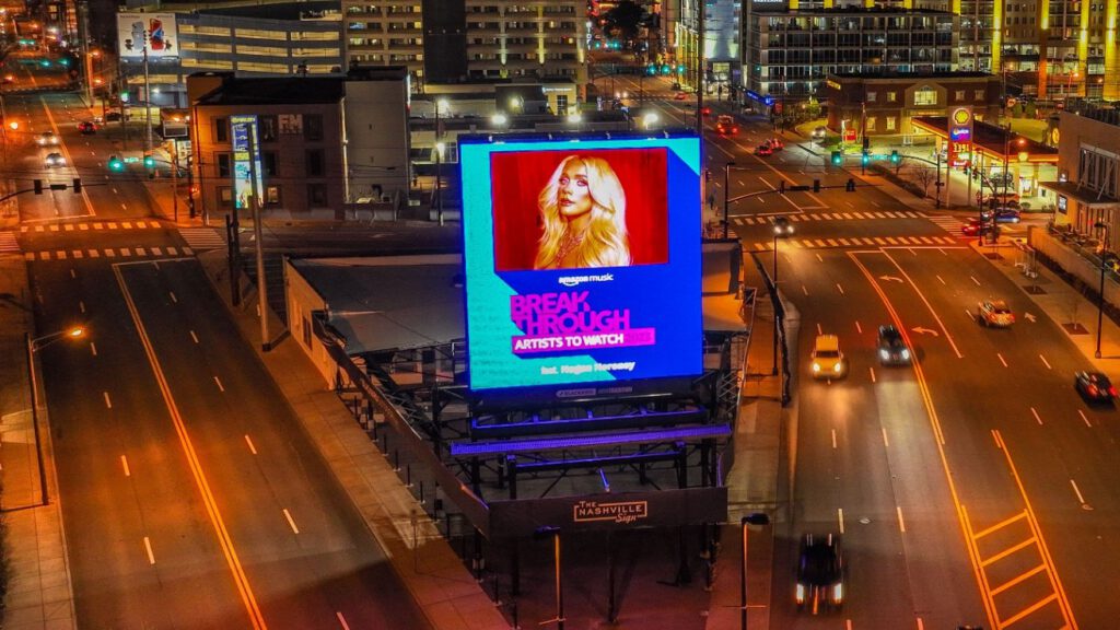 Bright digital billboard displaying a woman with long hair in Nashville at night.