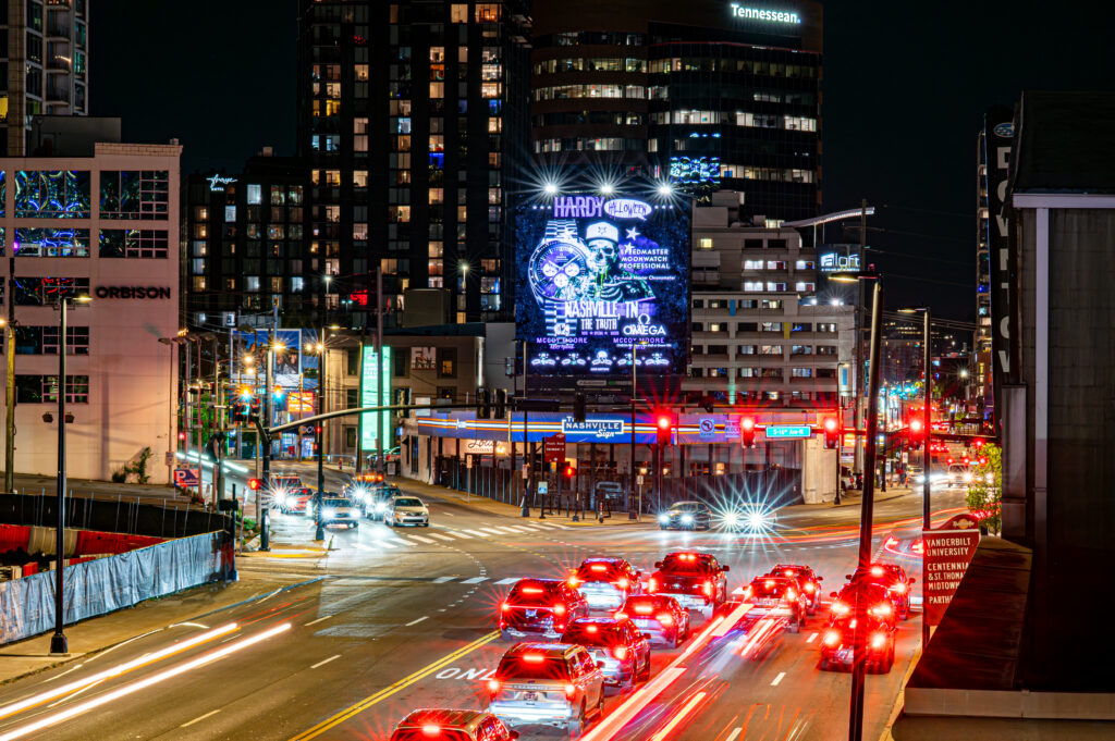 Vibrant city street at night with illuminated buildings and moving traffic.
