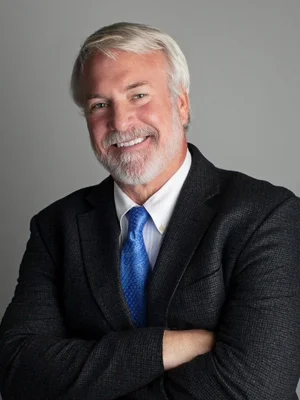 Smiling mature man in a suit with crossed arms for professional image.