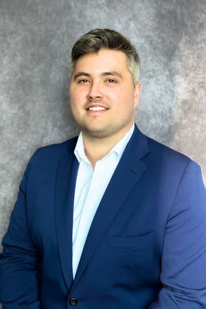 Businessman in a blue suit smiling for professional portrait.